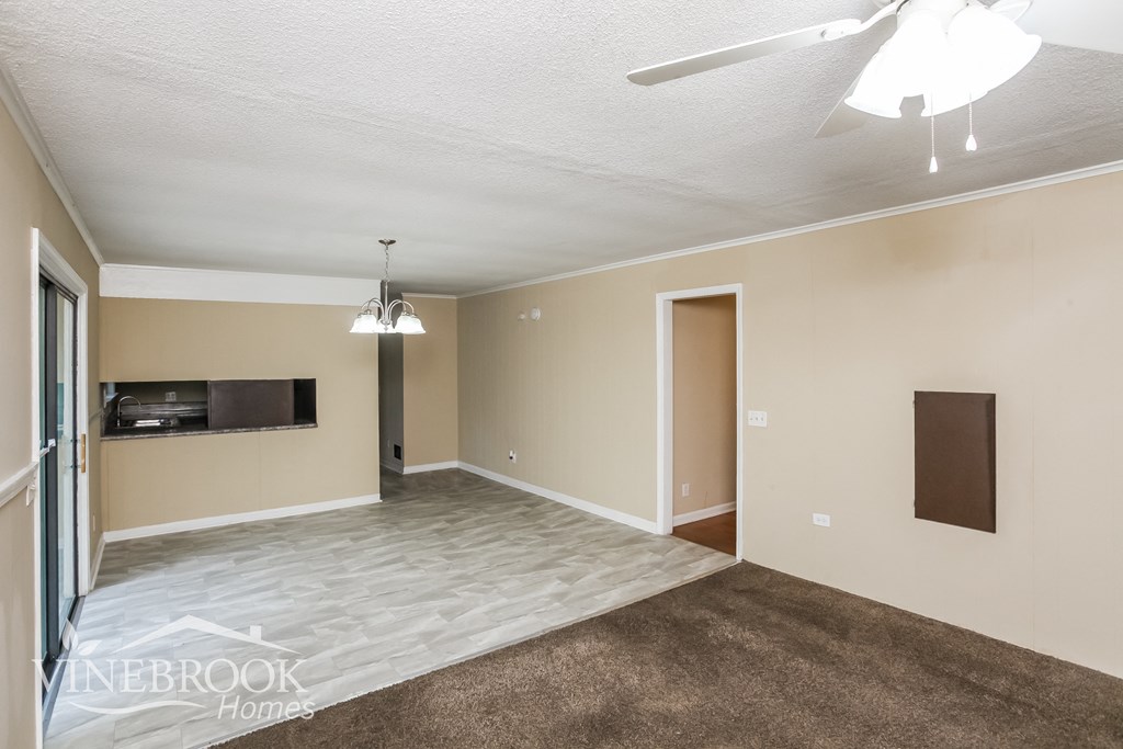 an empty living room with a tv and a ceiling fan