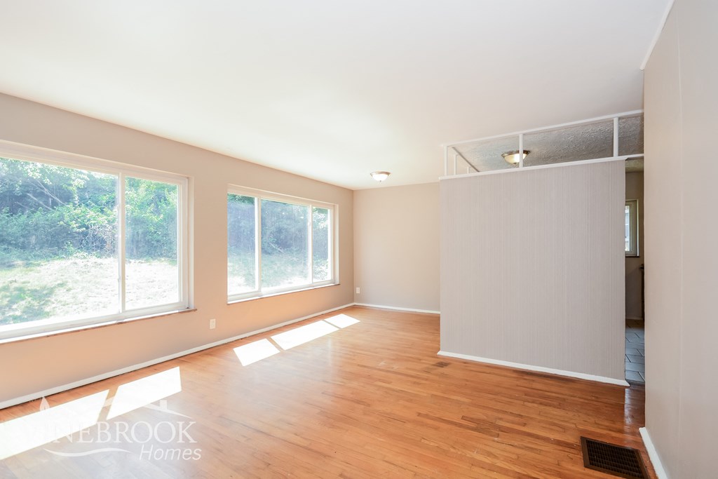 an empty living room with a hard wood floor and large windows