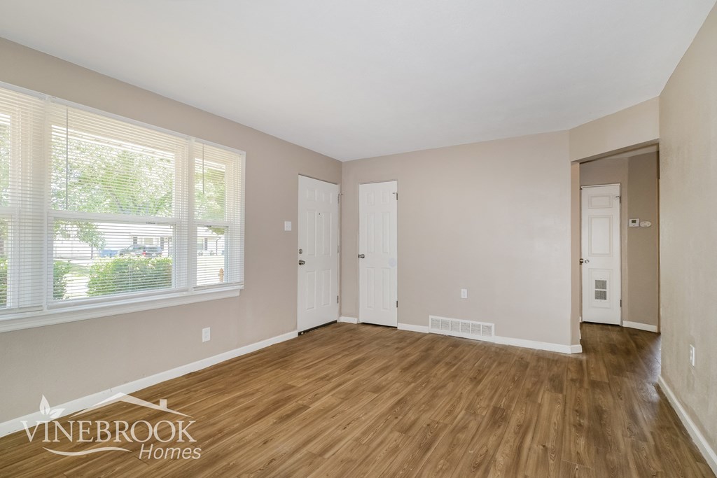 the living room of a home with wood flooring and a door to a hallway