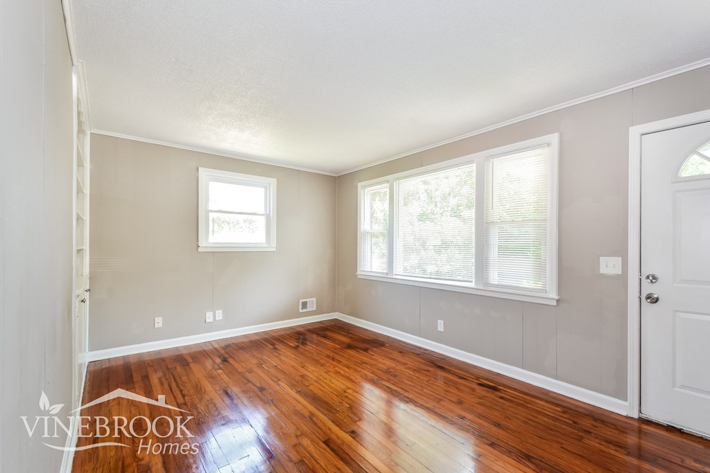 the living room has a hardwood floor and a door to the dining room