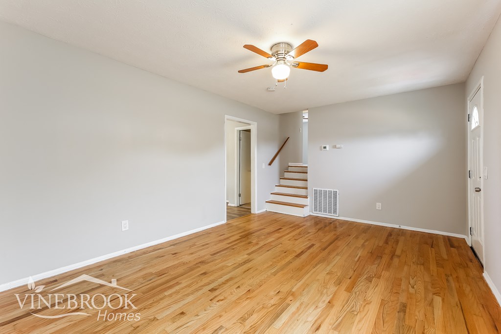 a living room with a wooden floor and a ceiling fan