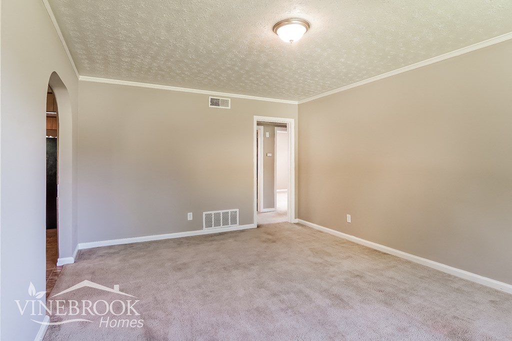 a empty living room with carpet and a door to a hallway