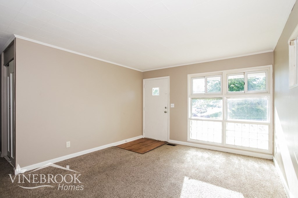 an empty living room with a door and window