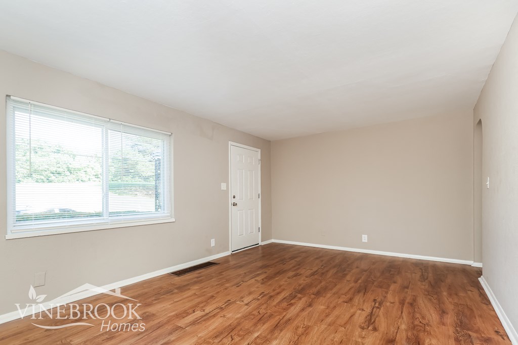 a living room with wood flooring and a window and a door