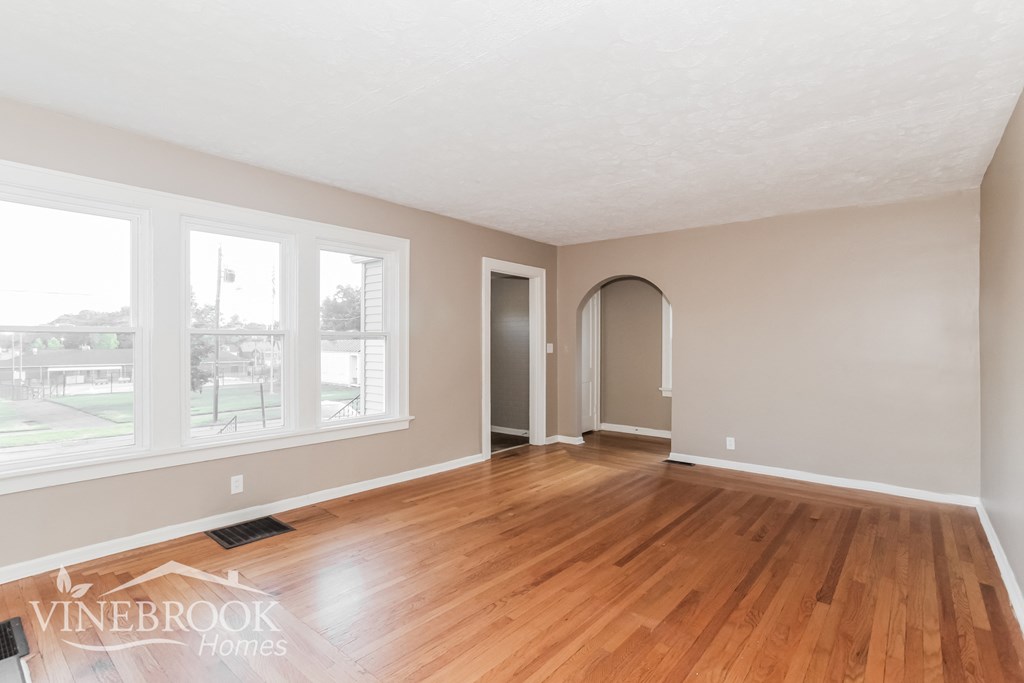 a living room with a hardwood floor and large windows