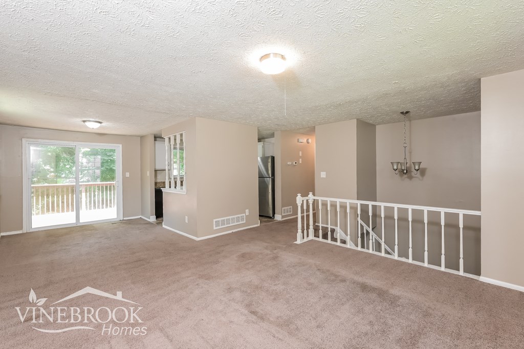 an empty living room with a staircase and a window