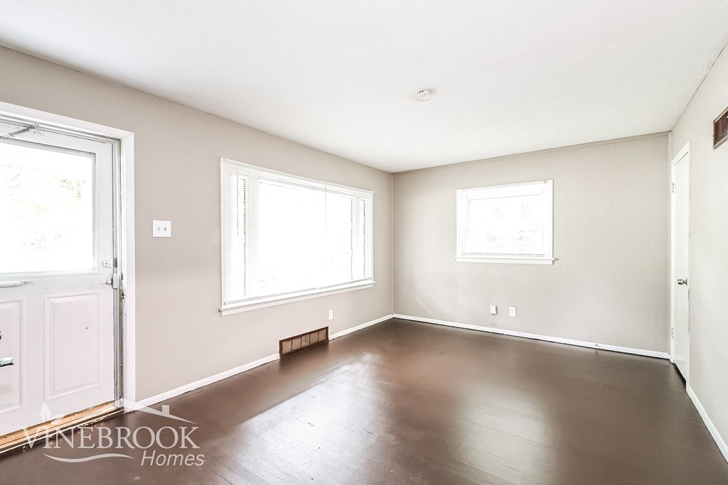 an empty living room with wood floors and white walls