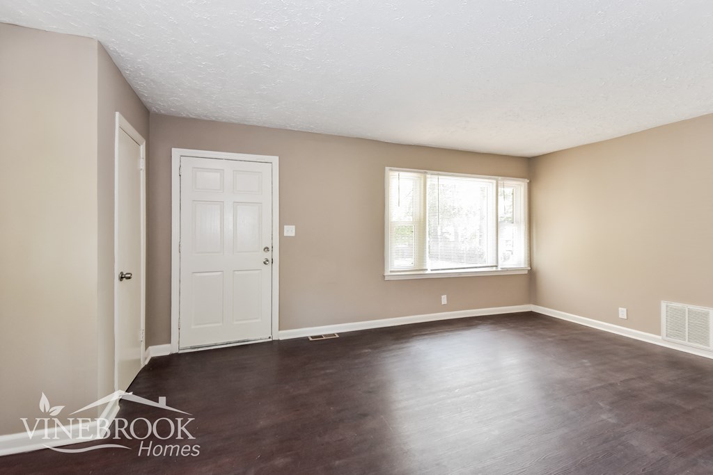 an empty living room with wood floors and a white door