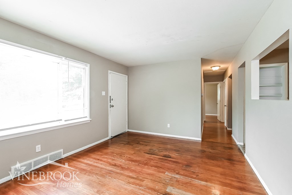 a renovated living room with wood floors and a large window