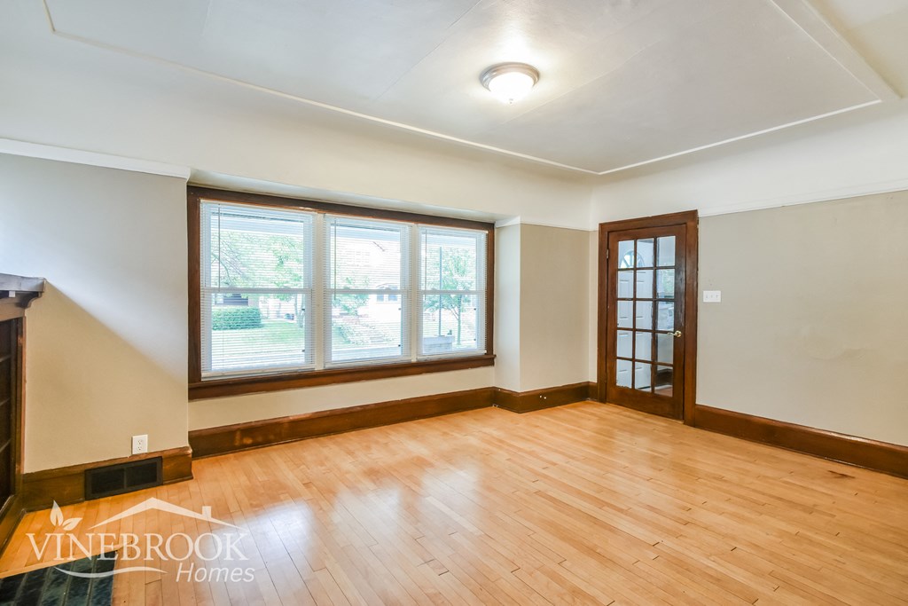 an empty living room with wood floors and a window
