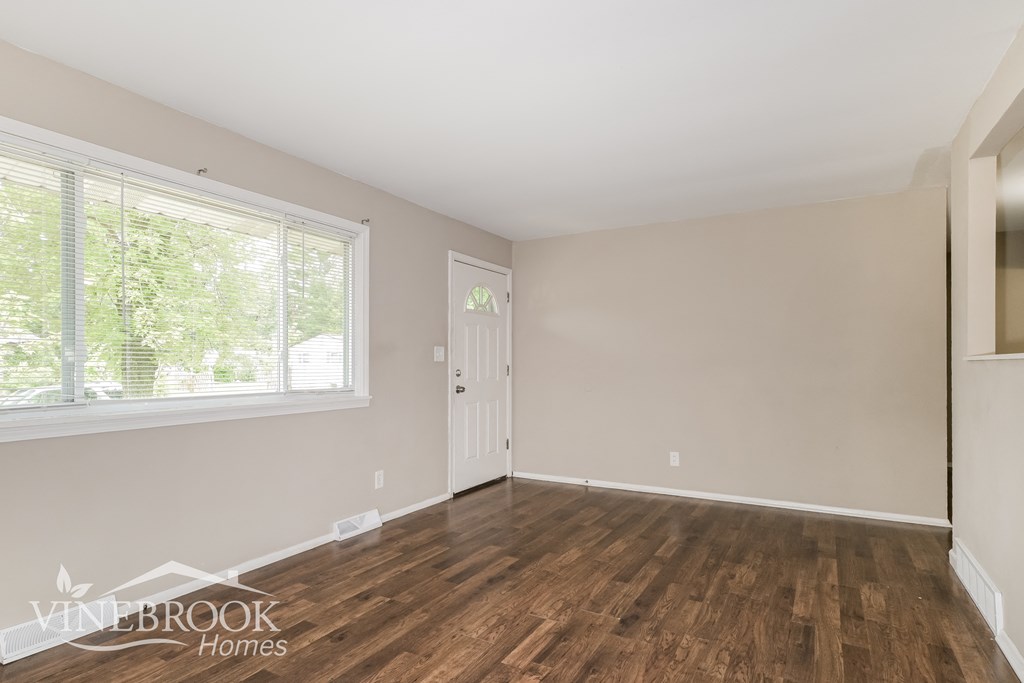 the living room of a home with wood floors and a white door
