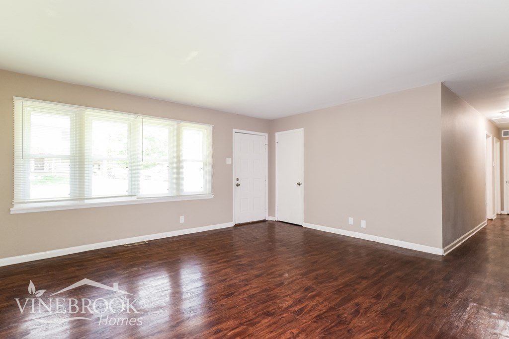 an empty living room with wood floors and white walls