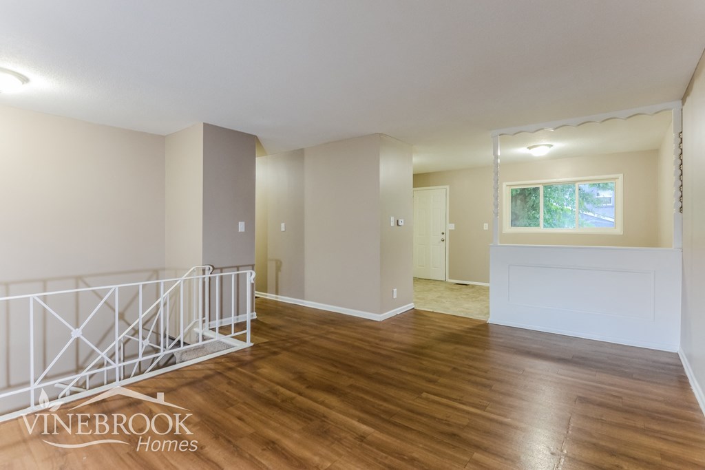 the living room and dining room of a home with wood floors and a staircase