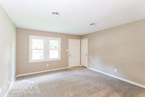 a bedroom with a carpeted floor and a white door and window