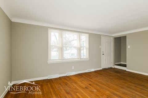 A room with wooden floors and a window with blinds.