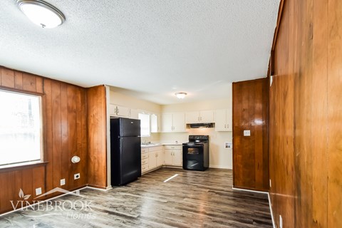 A kitchen with wood cabinets and a black fridge.