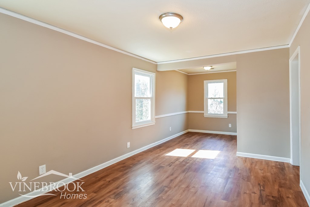 A room with wooden floors and two windows.