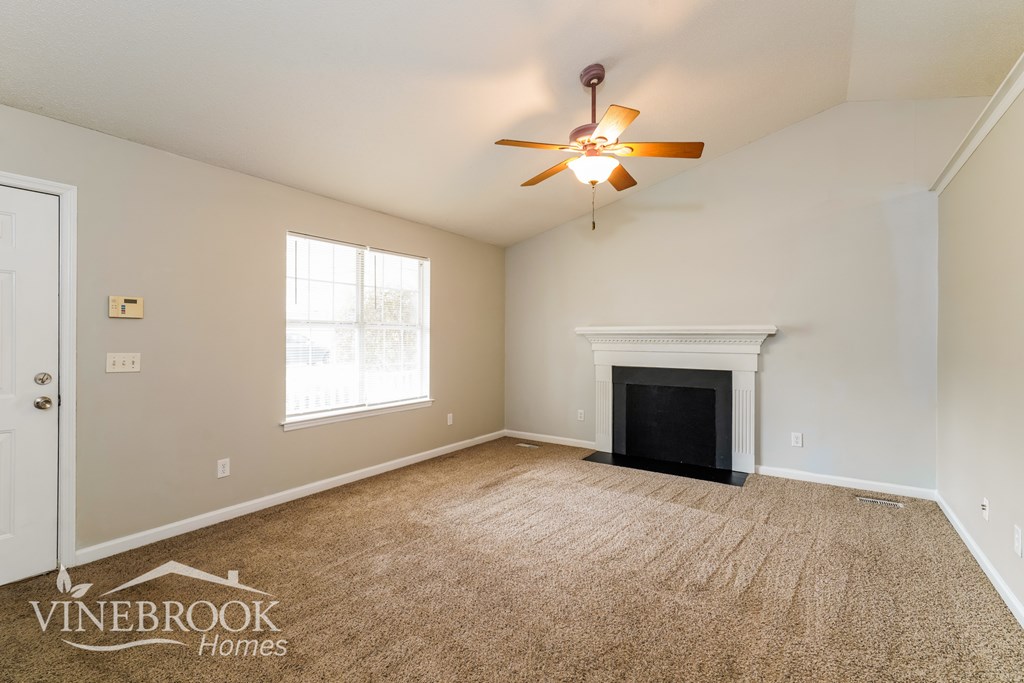 A room with a carpeted floor and a fireplace.