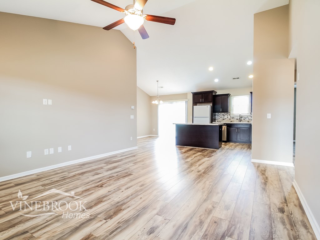 A spacious room with a ceiling fan and wooden flooring.