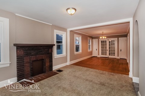 A living room with a fireplace and a carpet on the floor.