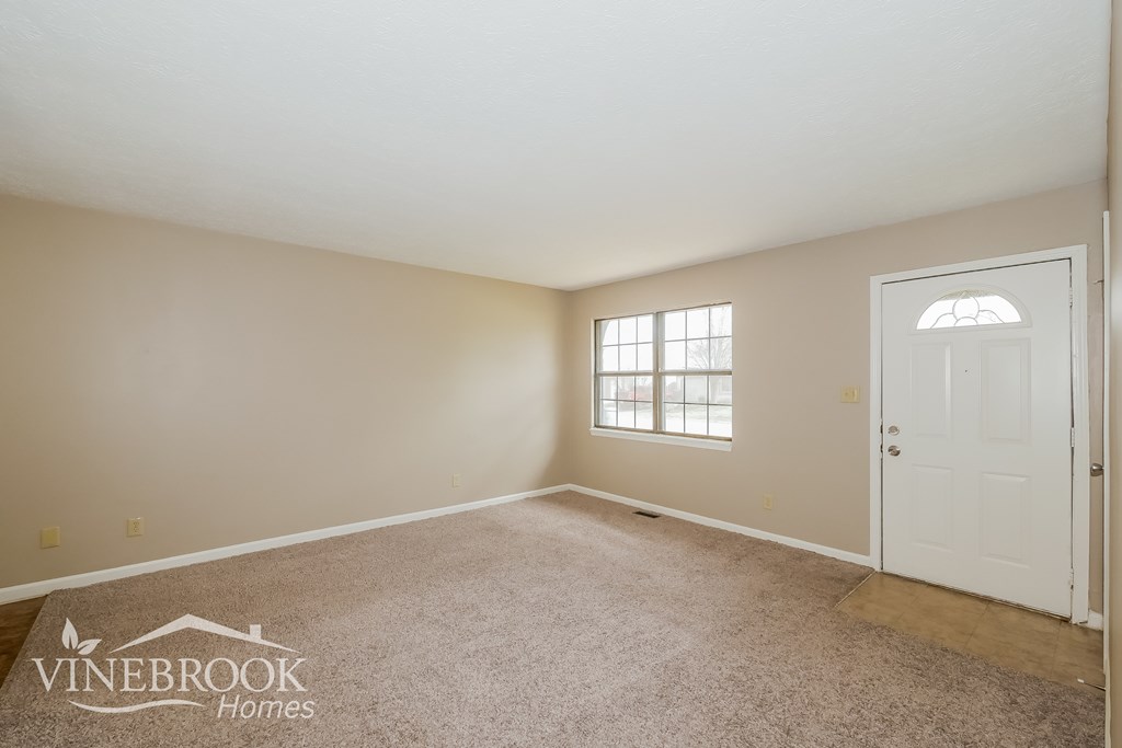 A room with a carpeted floor and a door is shown.
