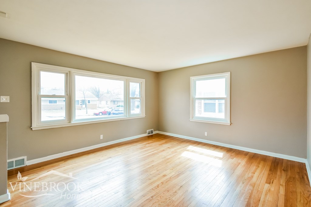 A room with wooden floors and two windows.