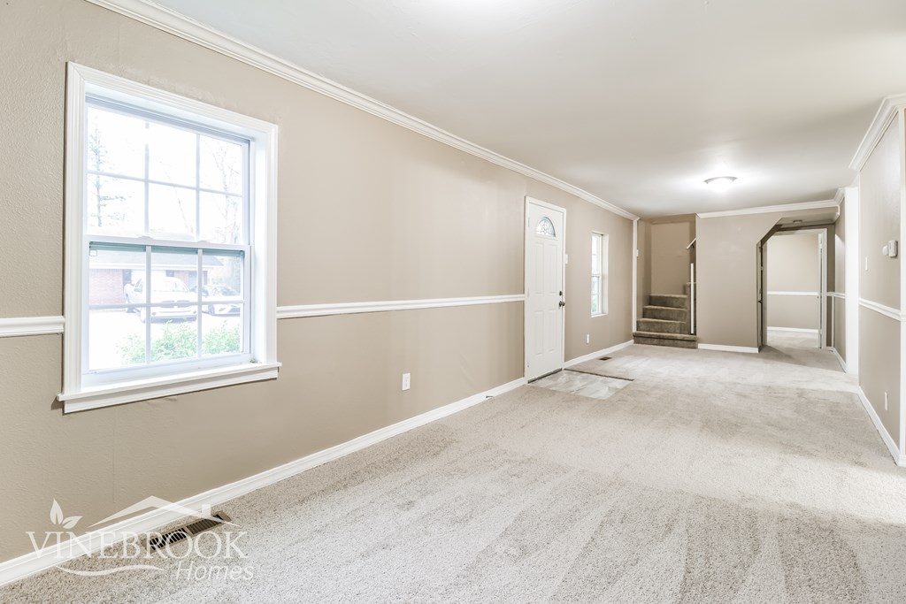 A room with a carpeted floor and a window.
