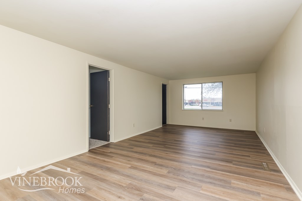 A room with wooden flooring and a window with a view of a street.