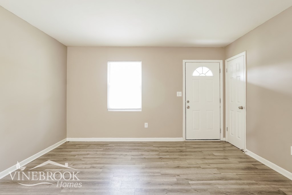 A room with a white door and a window with light coming through.