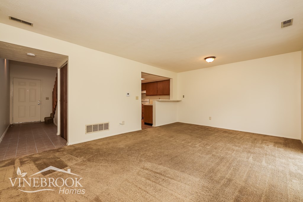 A room with a carpeted floor and a doorway leading to another room.
