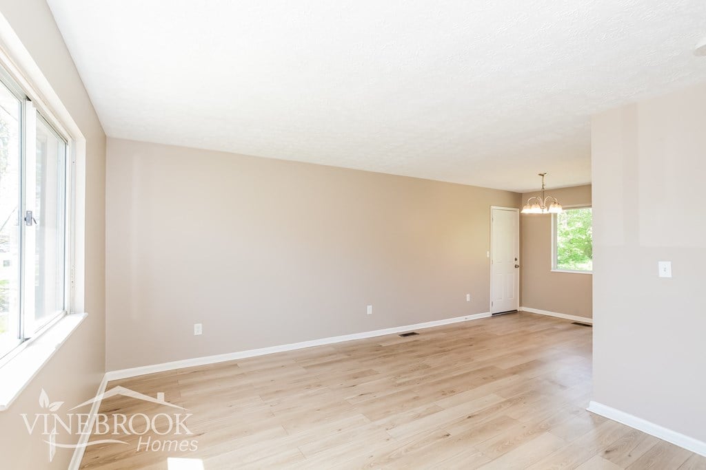 A room with wooden floors and a window on the left side.