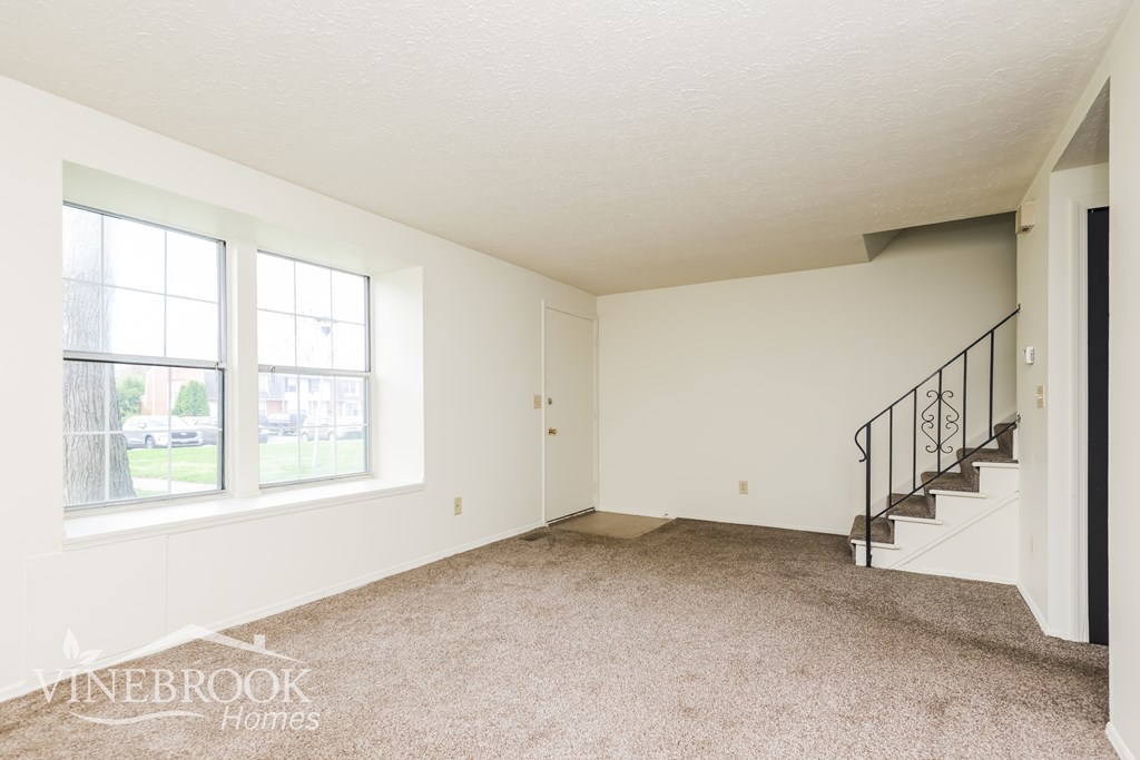 A room with a staircase and two windows.