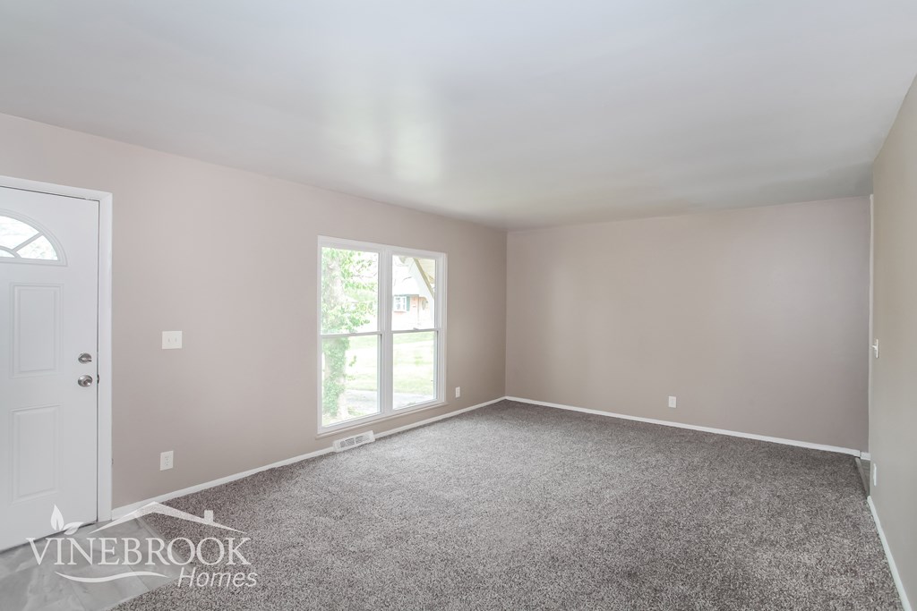 A room with a carpeted floor and a door leading to a balcony.