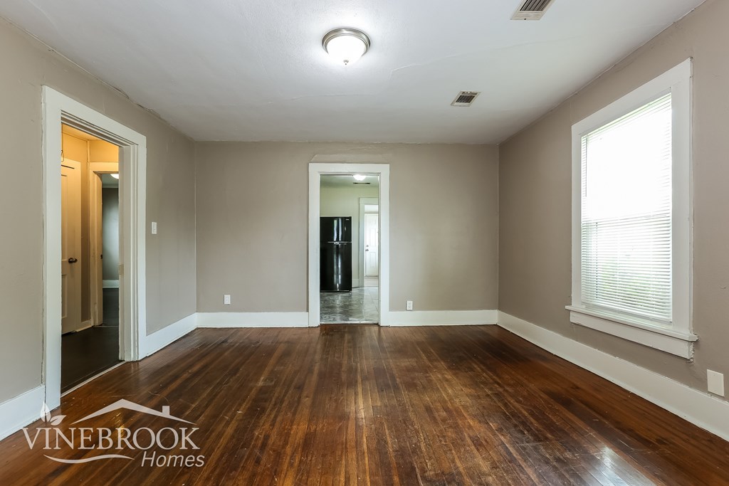 A room with wooden floors and a window on the right side.