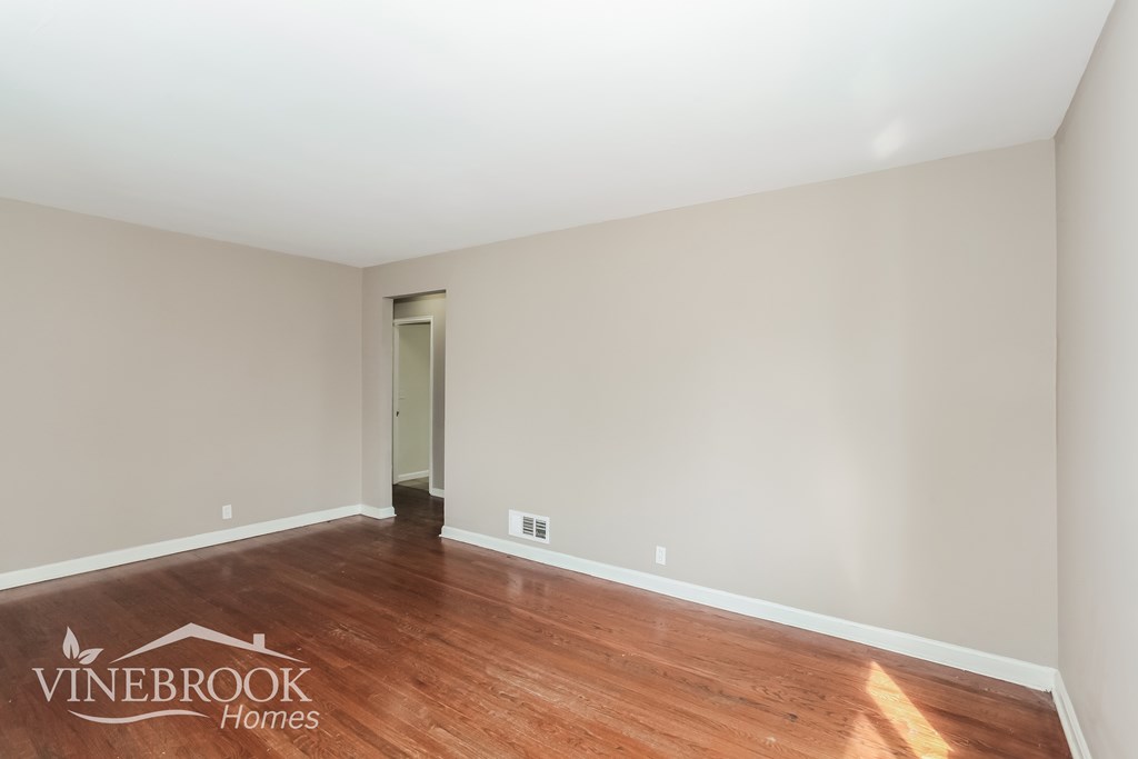 A room with wooden flooring and a doorway leading to another room.
