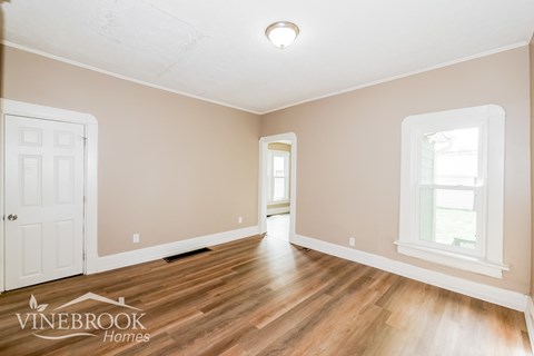 A room with wooden floors and a white door is shown.