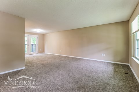 A spacious room with a carpeted floor and a door leading outside.