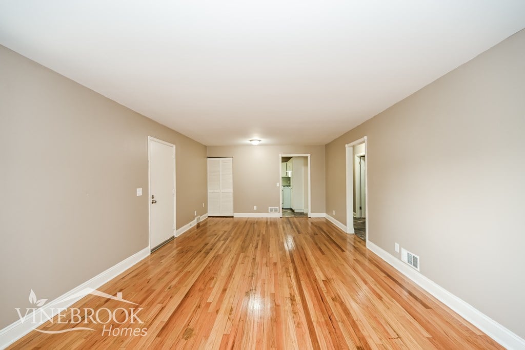 A long, empty hallway with wood floors and white walls.