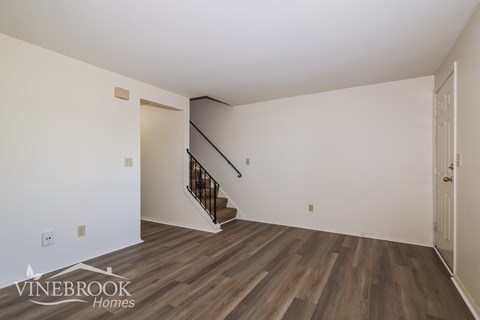 A room with a staircase and wooden flooring.