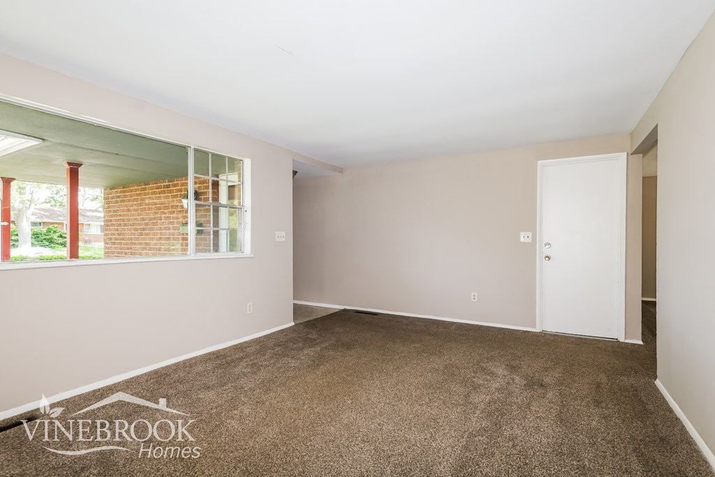 A room with a carpeted floor and a door leading to another room.
