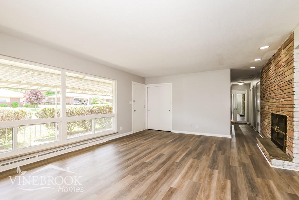 A room with wooden floors and a brick fireplace.