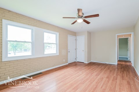 A room with a ceiling fan and wooden flooring.