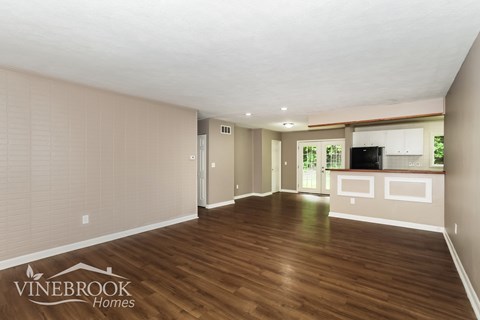 A room with wooden floors and a Vinebrook Homes logo.