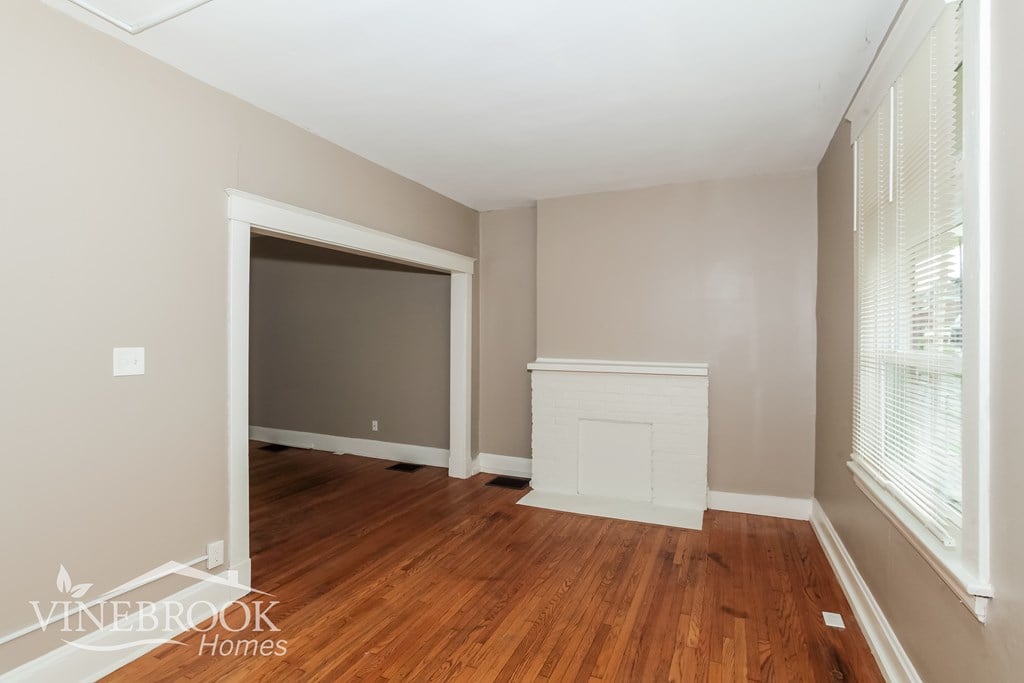 A room with a fireplace and wood flooring.