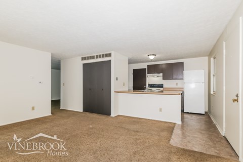 A Vinebrook Homes sign is on a carpeted floor in an empty room.