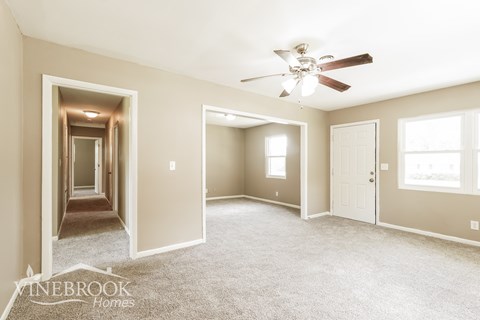 A spacious room with a carpeted floor and a ceiling fan.