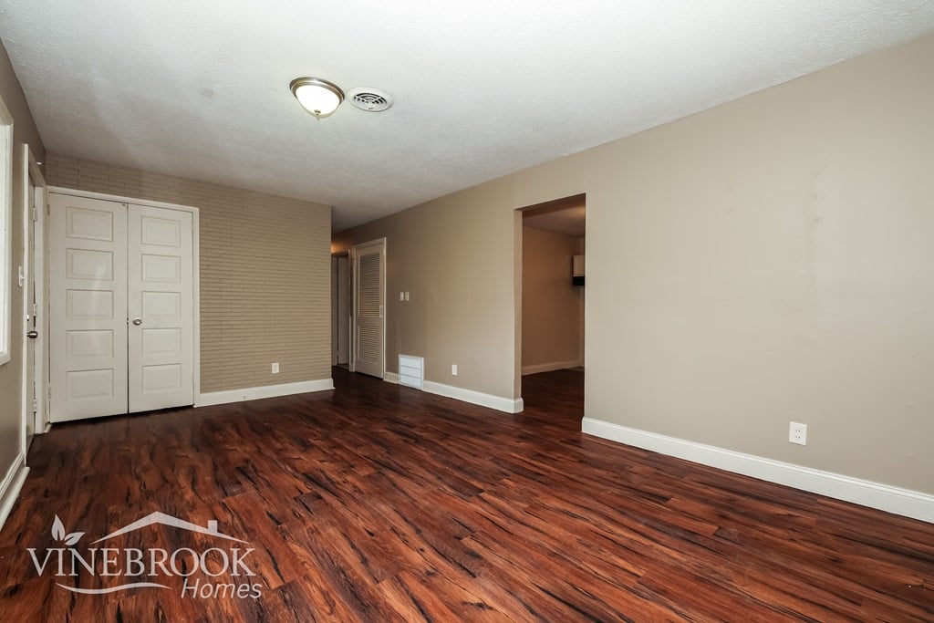 A room with wood flooring and a door on the left.