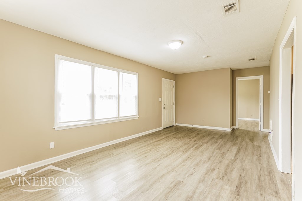 A room with a large window and wooden flooring.