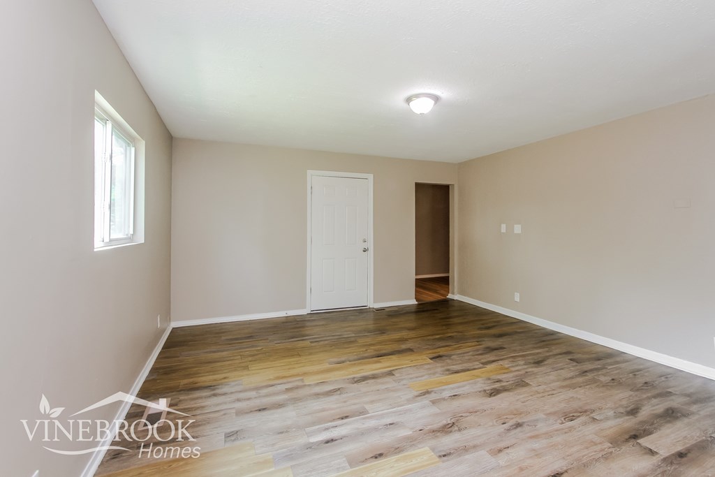 A room with wooden flooring and a white door.