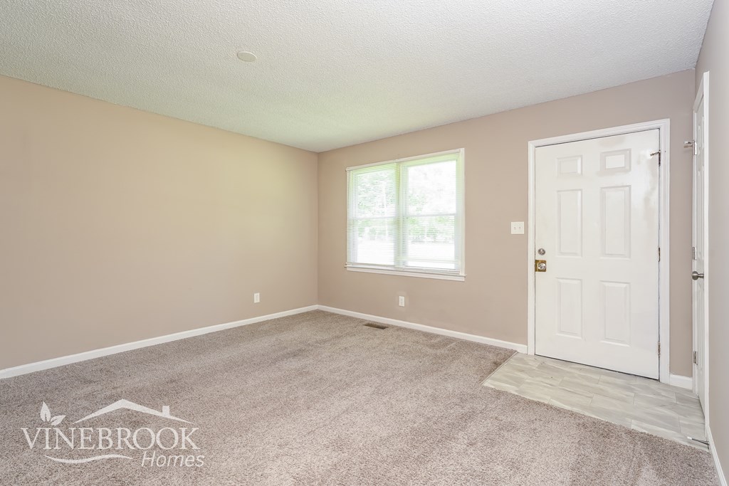 A room with a carpeted floor and a door on the right side.